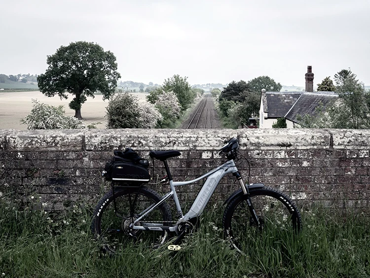 gray electric bike leaned against a stone fence