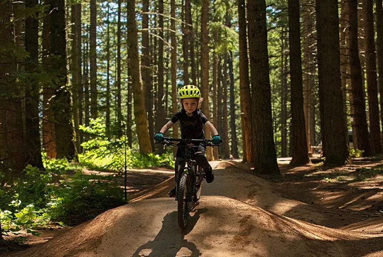 girl riding a mountain bike while wearing a kids bike helmet