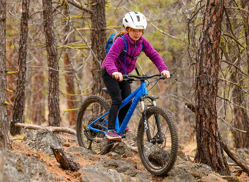 girl riding a 24 inch mountain bike in a forest