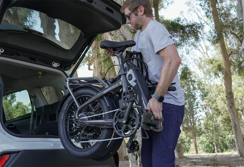 man lifting the folded ride1up portola ebike into his car trunk