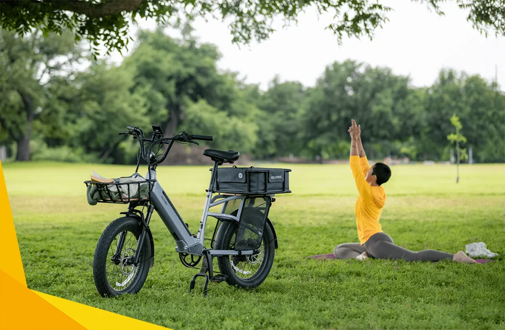 woman doing yoga next to a gray velotric electric bike