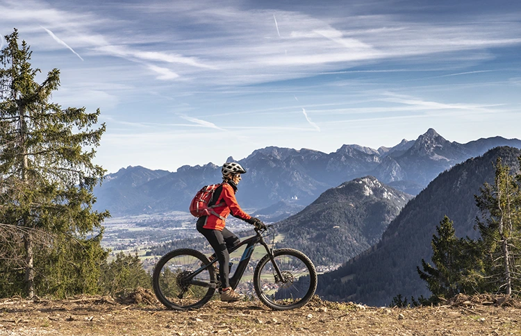 woman in red jacket riding a best electric mountain bike with mountains in the background