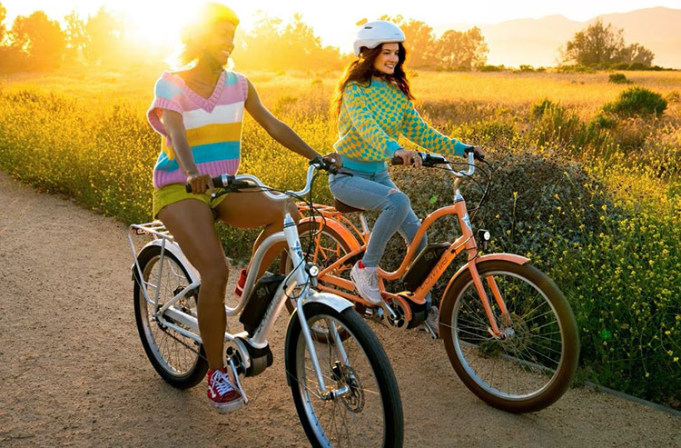 women riding electric townie bikes at sunset