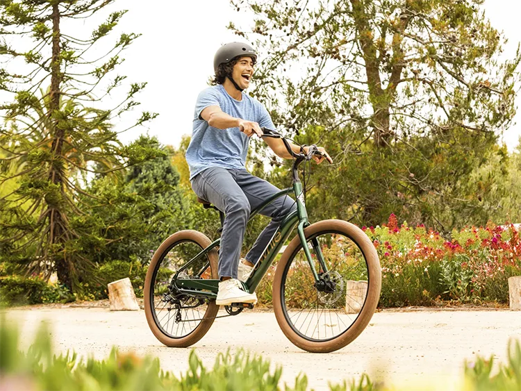 man riding a green electra townie bike with a big smile on his face