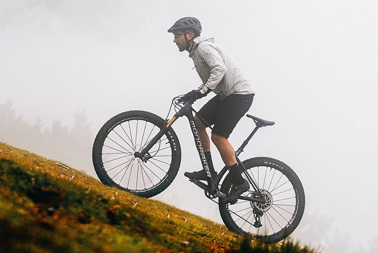 man climbing on a mondraker mountain bike