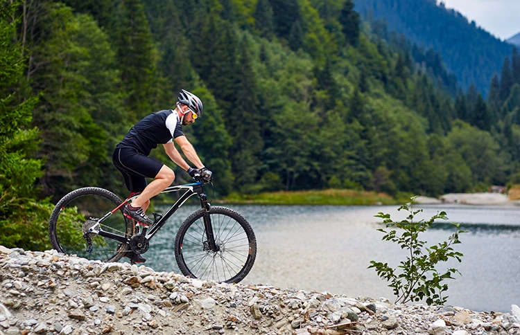 cyclist riding a mountain bike under 1000 next to a lake