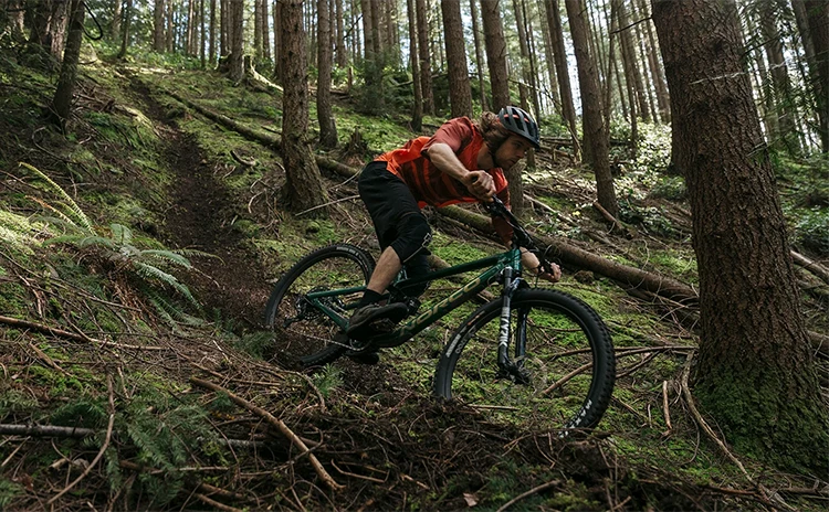 man descending a forest trail on a norco bikes mtb