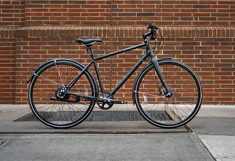 priority entry level hybrid bike leaning against a brick wall