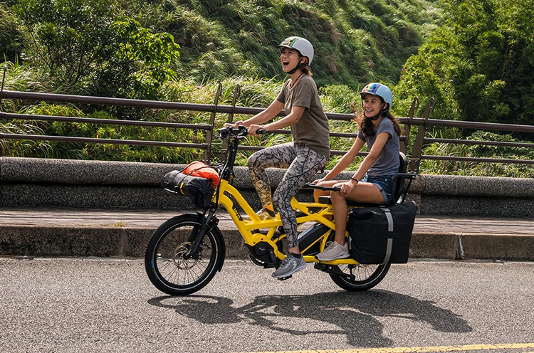 woman riding a tern electric bike with a child on the rear rack