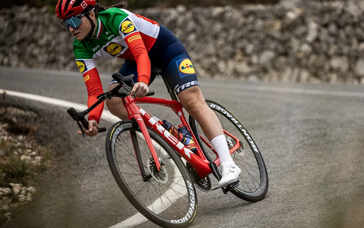 woman riding a red road bike made by the trek bikes brand