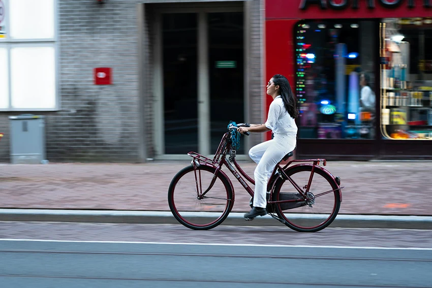 woman in white wearing a red dutch style bike